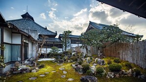 Een traditionele Japanse tuin met een houten omheining, mosbegroeide grond en stenen paden.