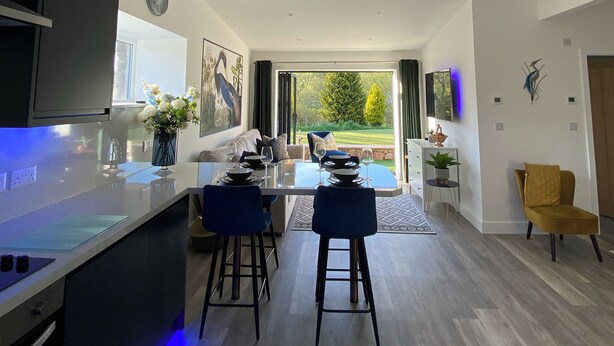 Een moderne keuken met een eethoek, een aan de muur bevestigde televisie en uitzicht op de omgeving.