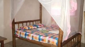 A single bed with a colorful quilt, a wooden frame, and a mosquito net. - Room-mida Creek Eco Camp Community Proje (Watamu)