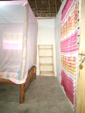Um quarto com cama, uma cadeira de madeira e uma parede com cortina estampada.