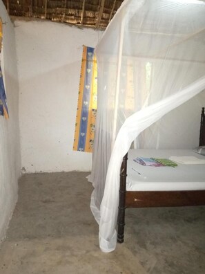 A room with a bed under a white canopy, a concrete floor, and a wall with a striped curtain. - Room-mida Creek Eco Camp Community Proje (Watamu)