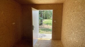 A room with a wooden interior and a door leading to an outdoor area with a lawn and trees.