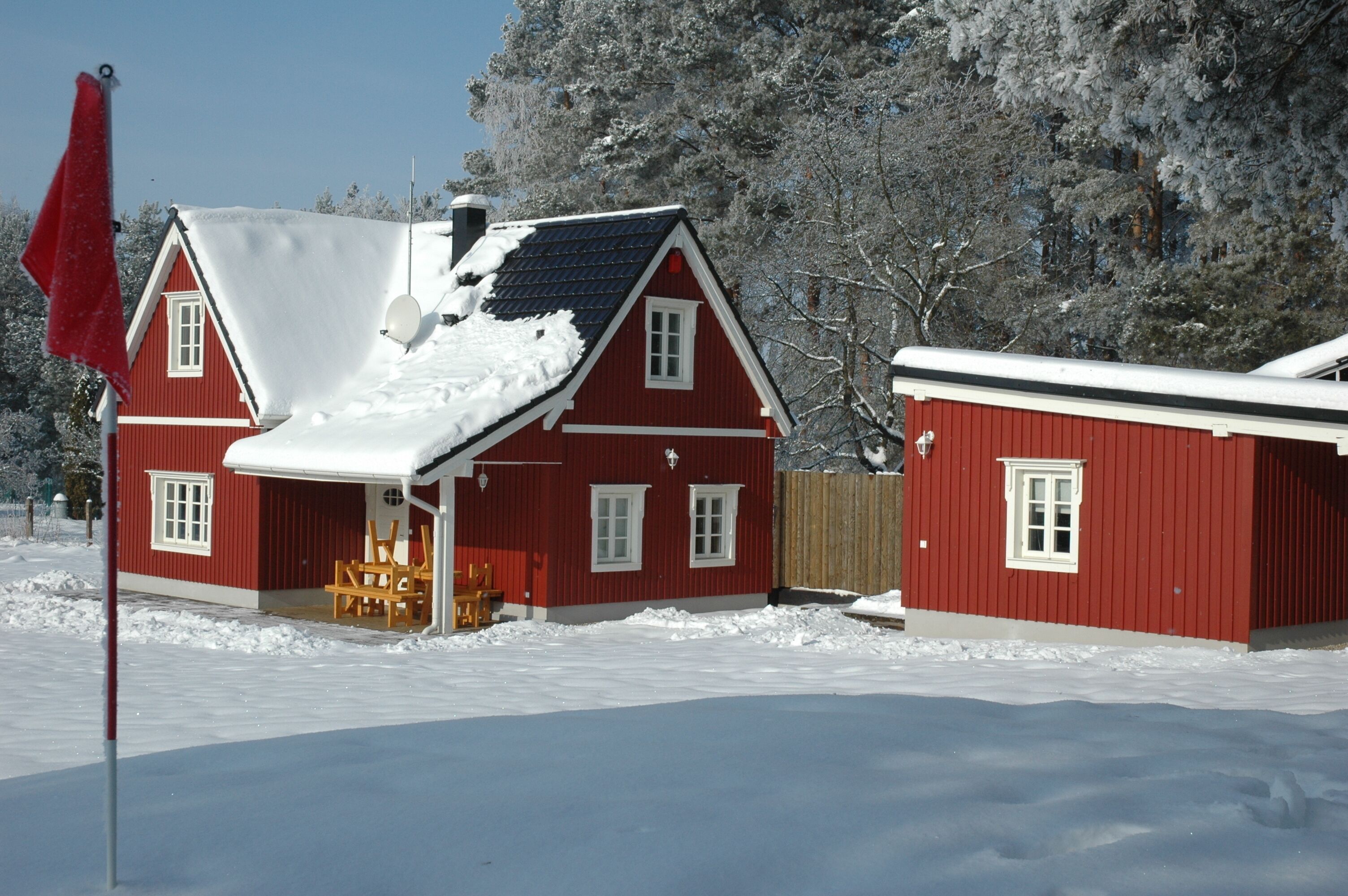Ein rotes Holzhaus mit schneebedecktem Dach und einer kleinen Veranda.