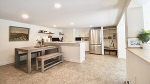 Een moderne keuken met een centraal eiland, inbouwapparatuur en een eethoek met een bank.