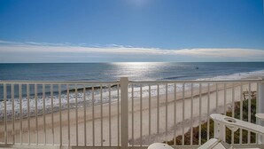 En balkon med udsigt over strand og hav.