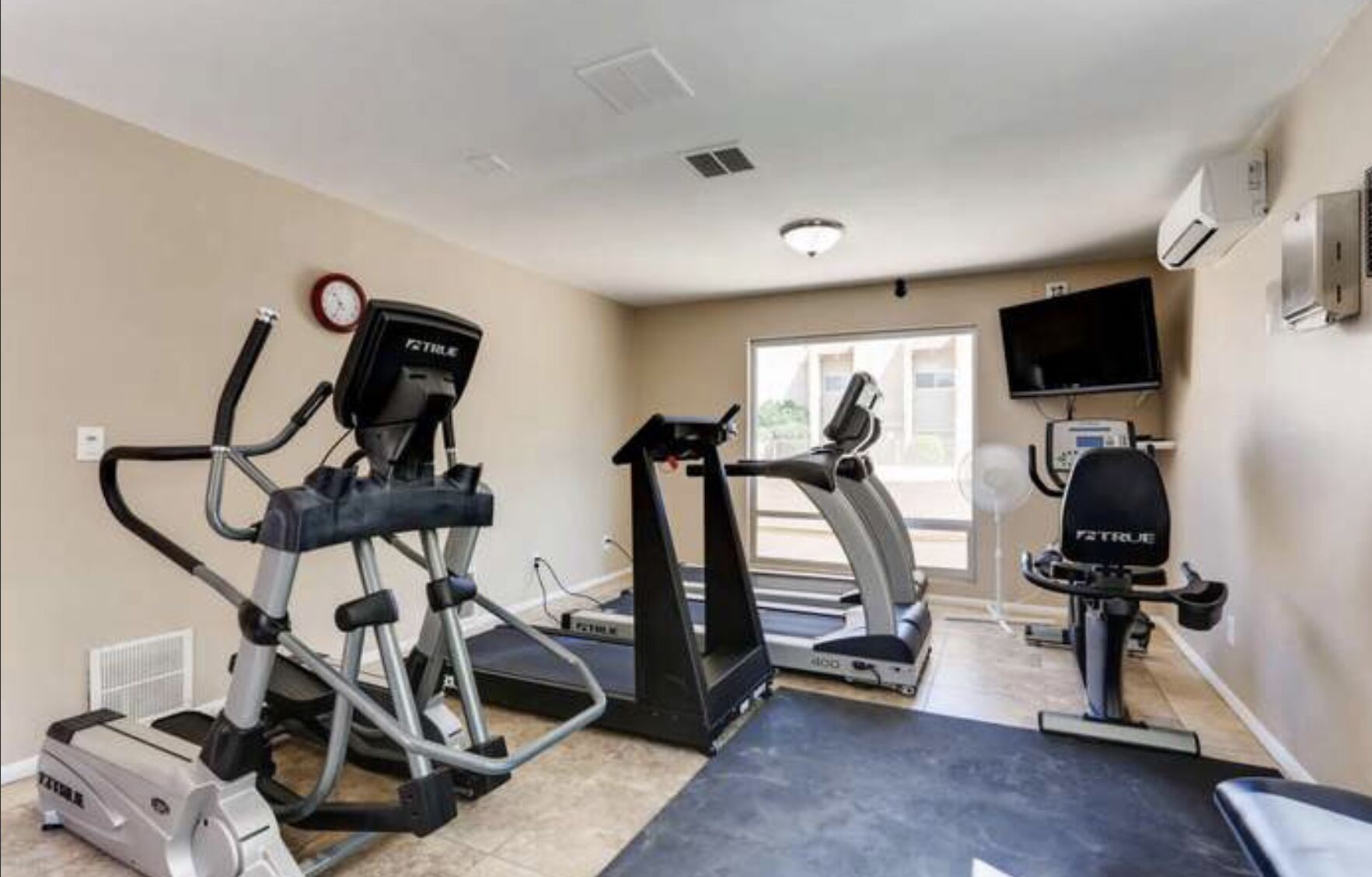 A home gym with treadmills, an elliptical, and a stationary bike.