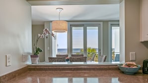 A kitchen with a view of the ocean, a hanging light fixture, and a bowl of fruit on the counter. - Sunkissed Escape with spectacular views (Fernandina Beach)