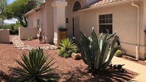 A house with a tiled roof, arched doorway, and a garden with agave plants. - Southwestern Patio Home-Magnificent Mountain Views (Oro Valley)