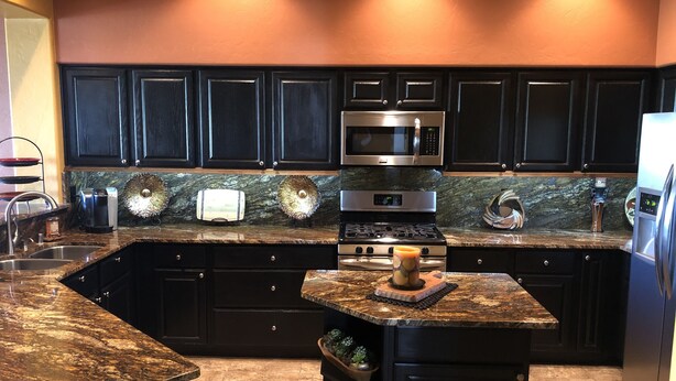 A kitchen with dark cabinets, a granite countertop, a stainless steel microwave, a stove, and a sink. - Southwestern Patio Home-Magnificent Mountain Views (Oro Valley)