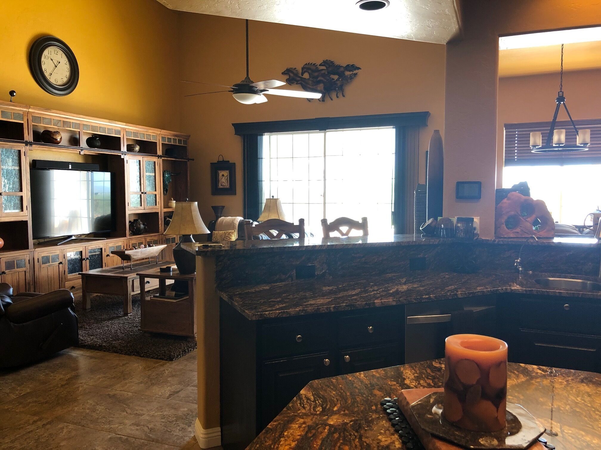 A spacious kitchen with a large island, built-in cabinets, and a television.