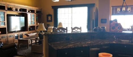 A spacious kitchen with a large island, built-in cabinets, and a television.