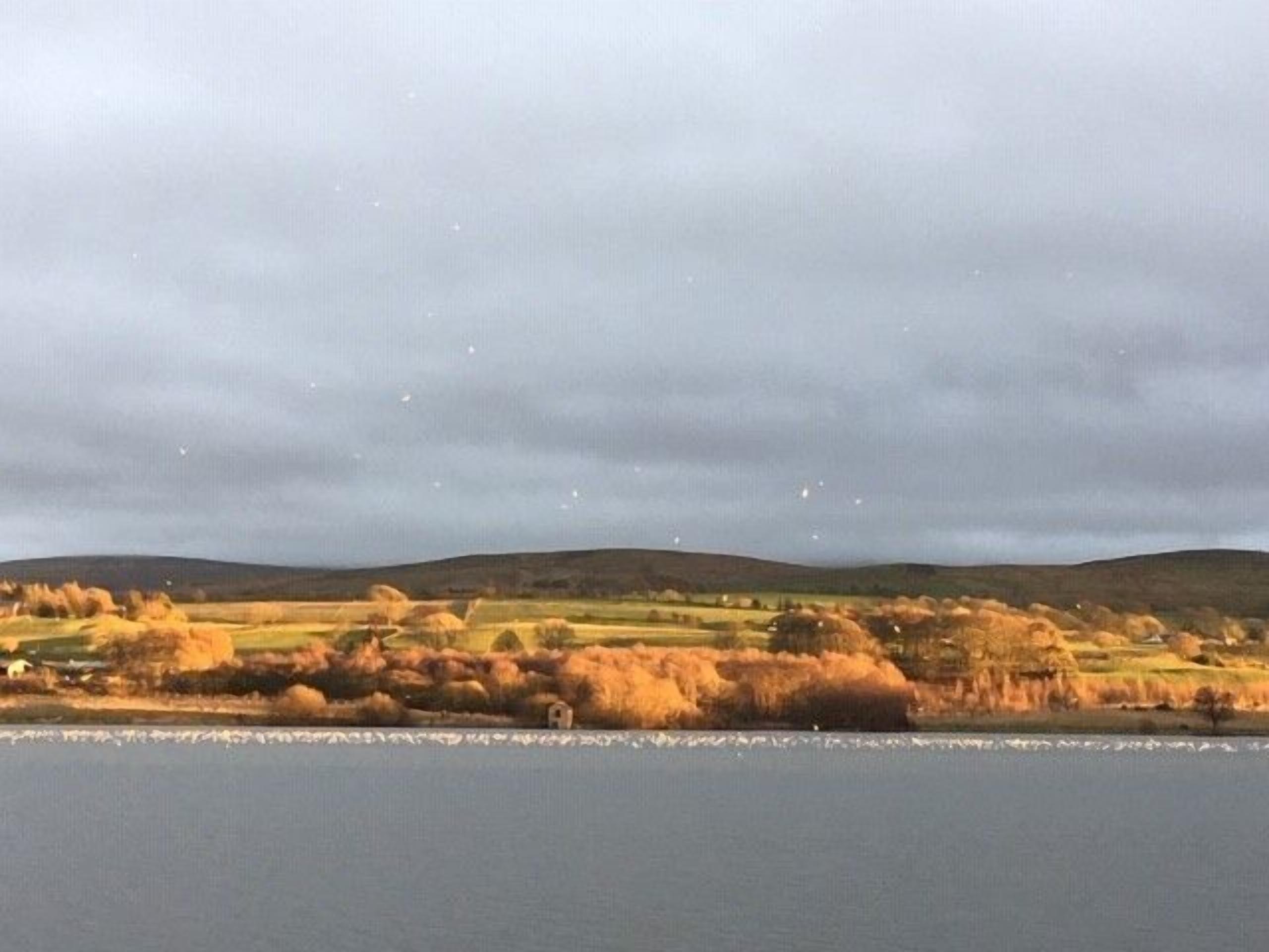 Un paysage comprenant une étendue d’eau, des collines douces et une végétation clairsemée.