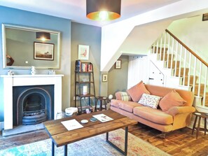 A living room with a fireplace, a sofa, a coffee table, and a staircase.