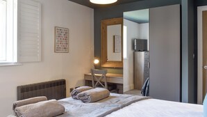 Una camera da letto con un letto, una scrivania, una sedia, un termosifone e uno specchio.