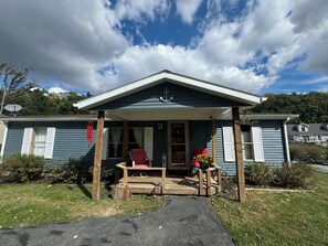 A house with a porch, a red chair, and a wooden bench.
