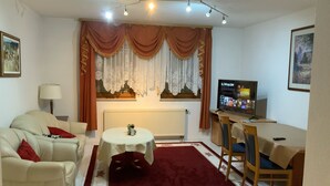 Un salon avec un canapé, une petite table, un téléviseur et un radiateur.