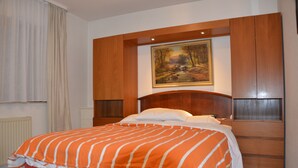 Une chambre à coucher avec un grand lit, une tête de lit en bois et un tableau accroché au-dessus du lit.