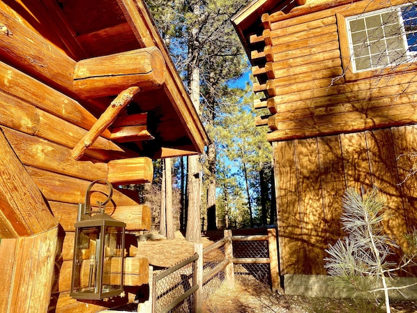 A wooden cabin with a porch, a lantern, and a pine tree in the background. - Enchanted Log Home on Large Lot Pet friendly (Big Bear Lake)