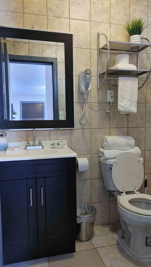 A bathroom with a sink, mirror, toilet, and a telephone. - The White Bungalow (Rosarito)