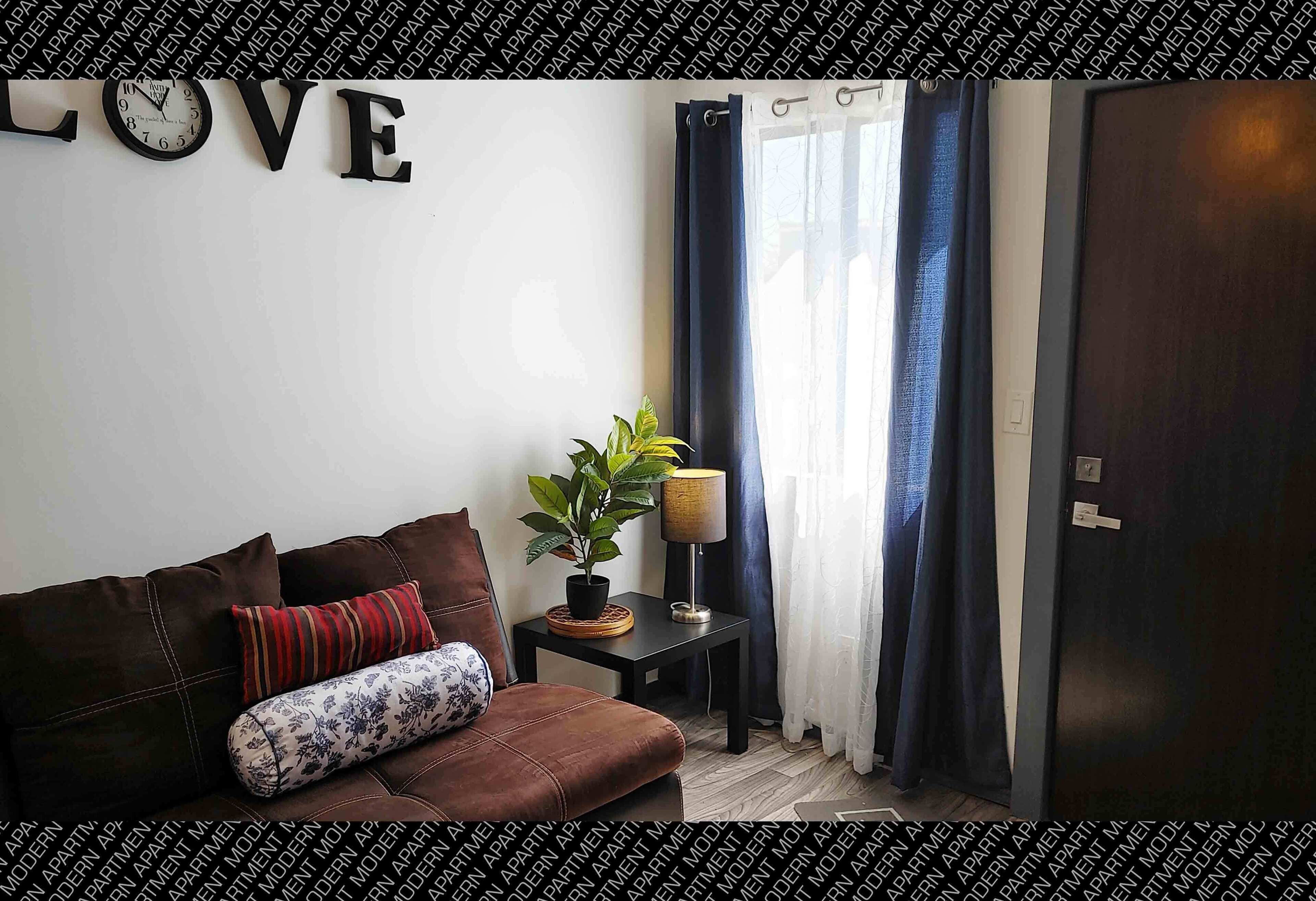 Un salon moderne avec un canapé, un élément décoratif mural, une plante en pot et une lampe.