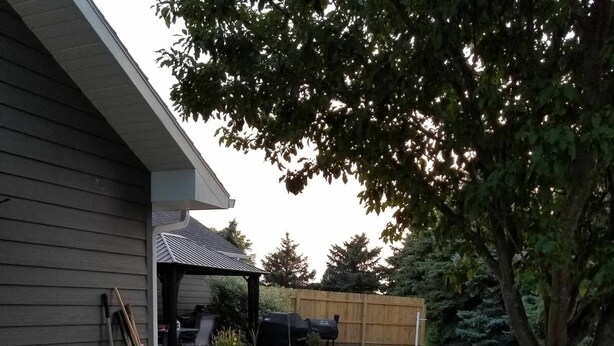 A modern outdoor patio with a fire pit, a covered seating area, and a wooden fence.