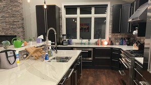 A modern kitchen with a large island, dark cabinetry, and a stone accent wall.