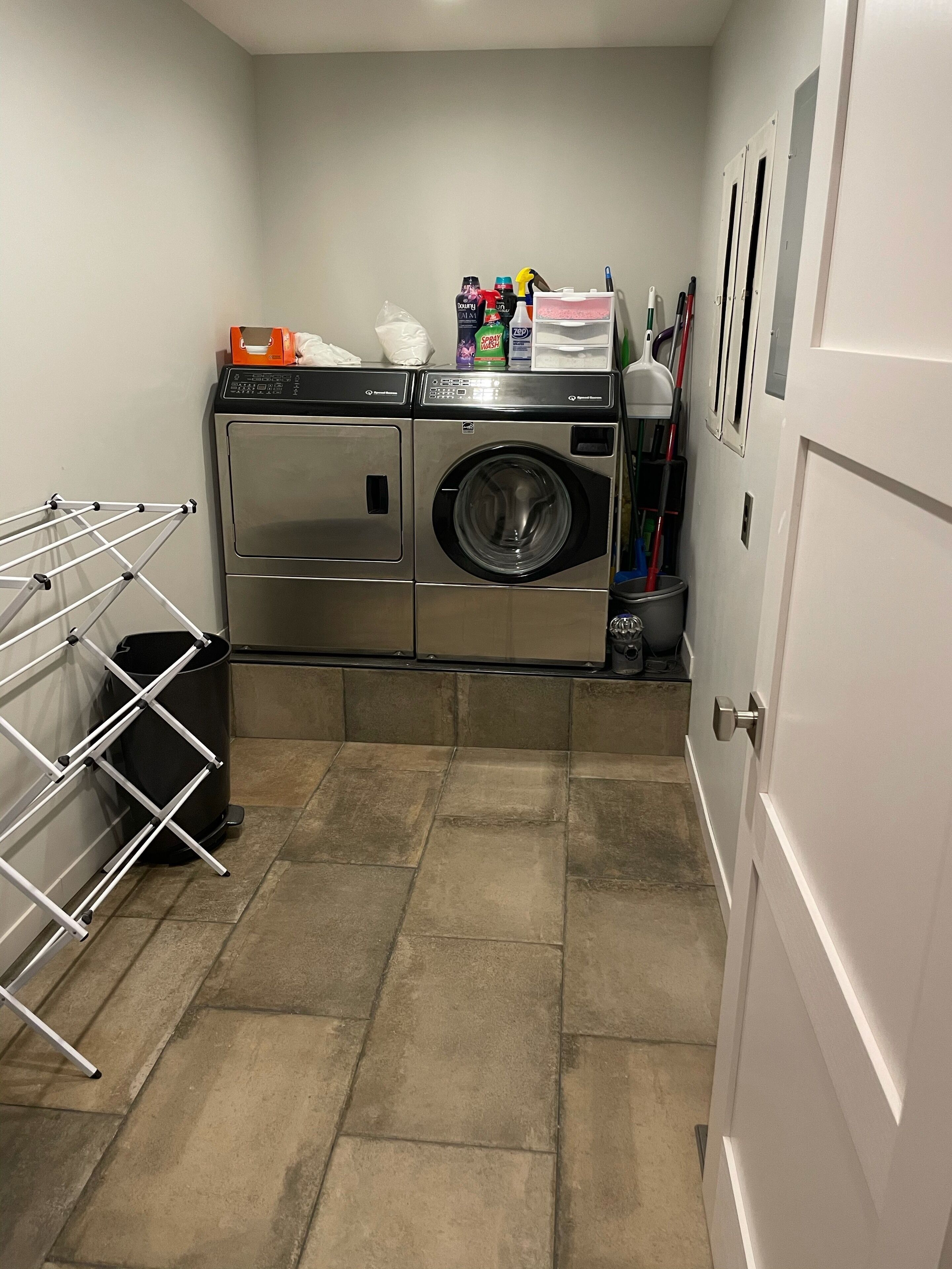 A laundry room with a washing machine, dryer, and a drying rack.