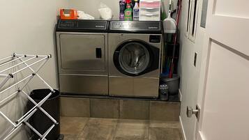 A laundry room with a washing machine, dryer, and a drying rack.