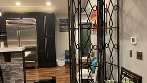 A modern kitchen with dark cabinets, a stainless steel refrigerator, and a wooden floor.