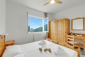 Habitación de hotel con cama, armario de madera, escritorio y ventana con vista a la montaña.