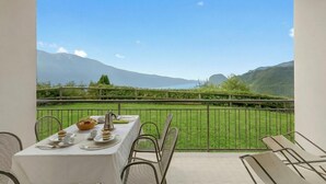 A dining table set with plates, bowls, and cutlery, overlooking a grassy area with mountains in the background. - Bellevue Modern Apartment 6, Tremosine, Italy (Tremosine)