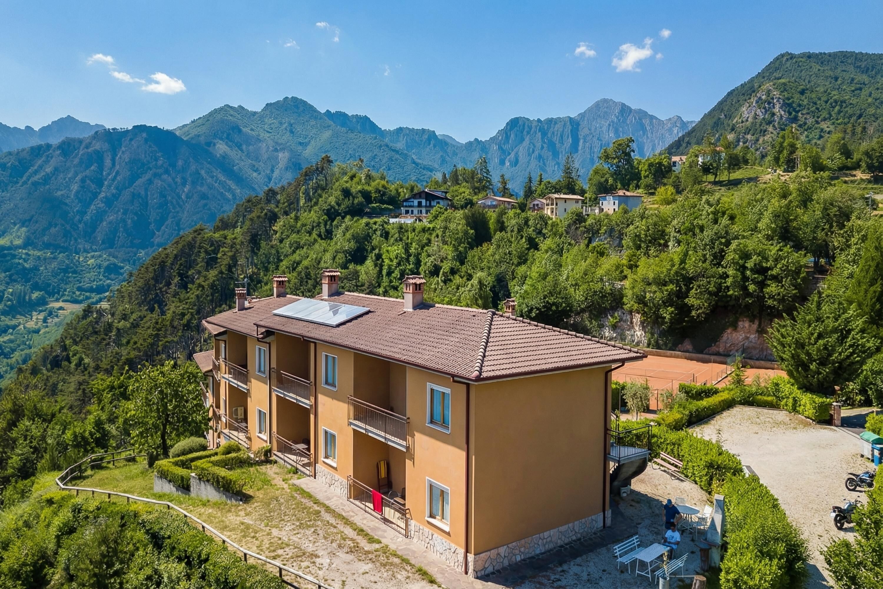 A multi-story building with balconies, a paved patio, and a mountain backdrop.