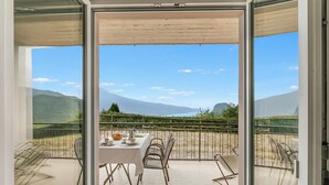 A balcony with a table set for dining, a chair, and a view of the mountains.