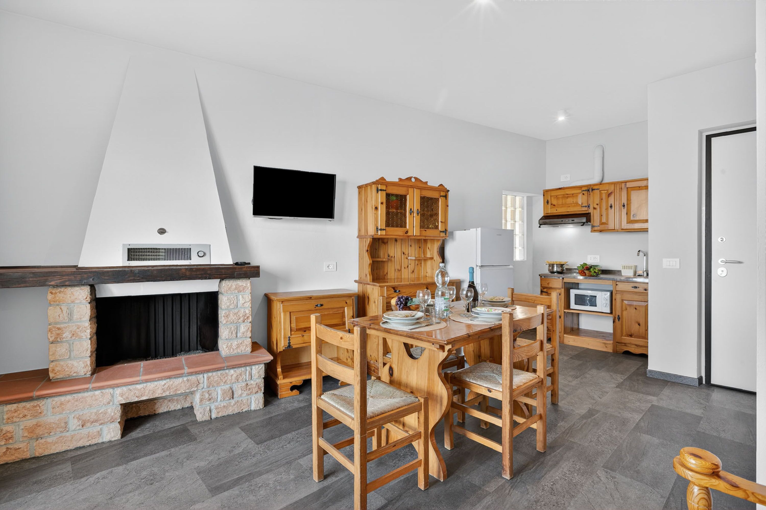 Een moderne keuken met een open haard, houten kastjes en een eethoek met stoelen.