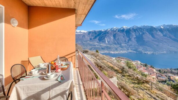 A balcony with a table set for dining, overlooking a mountainous landscape and a body of water. - Residence Bellevue 3, Tremosine, Italy (Tremosine)
