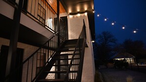 Un edificio de varios pisos con una escalera, un balcón y luces colgantes.