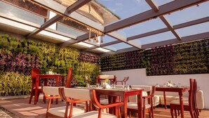 Een restaurant met houten meubilair en een groene wand vol planten.