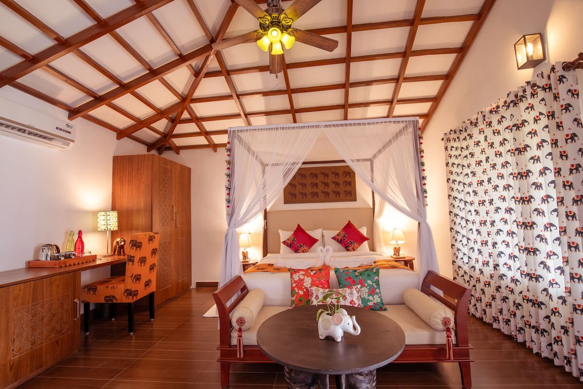 A bedroom with a canopy bed, a wooden desk, and a dining table.
