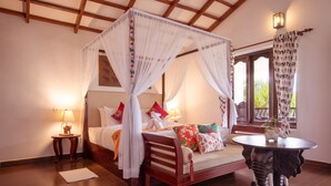 Een slaapkamer met een hemelbed, een nachtkastje met een lamp en een decoratieve olifant poten.