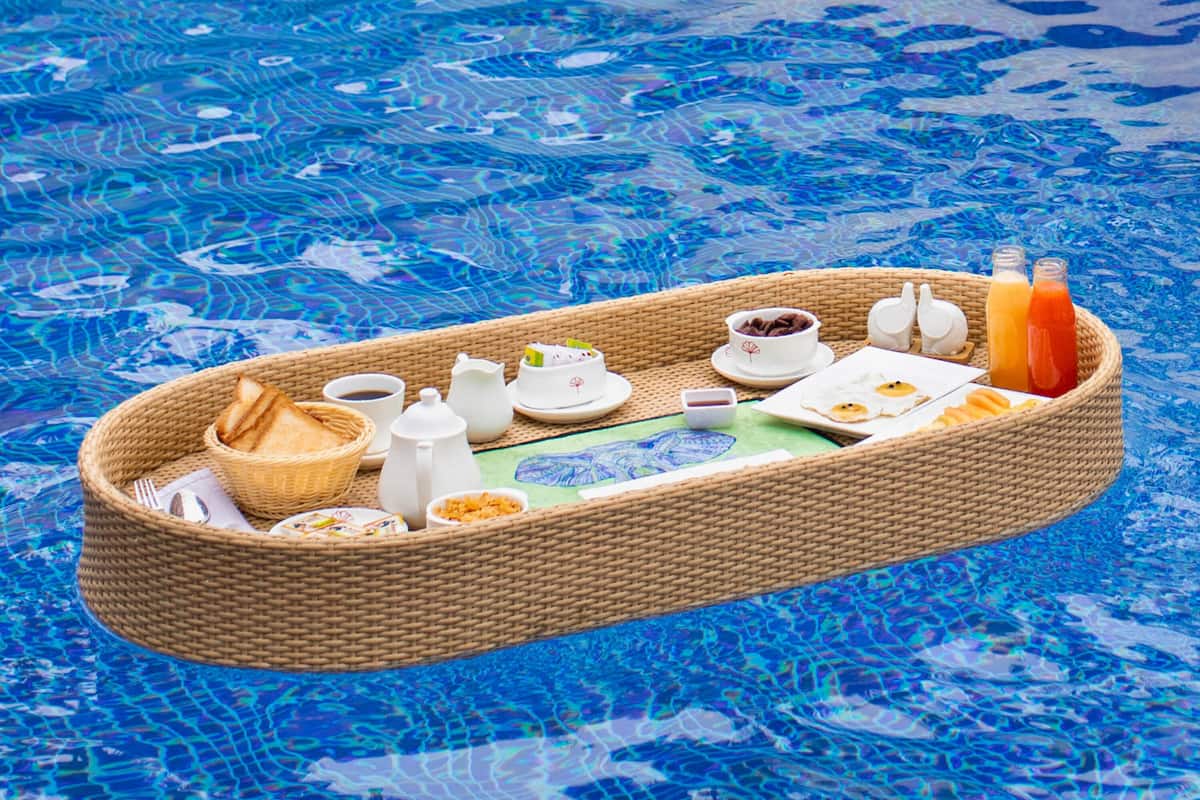 A floating tray with food and drinks on a pool.