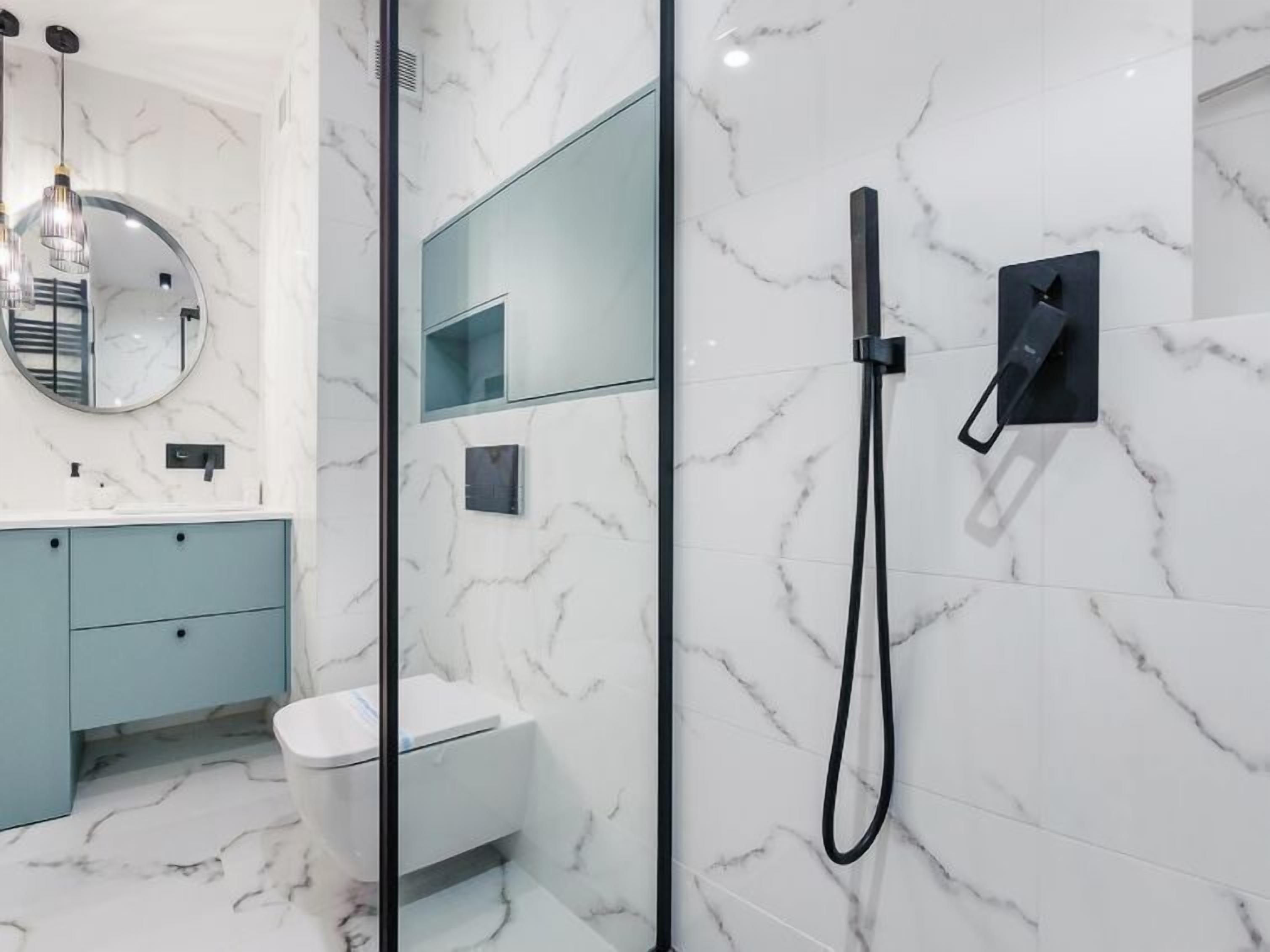 A modern bathroom with a glass shower enclosure, a toilet, and a vanity with a mirror.