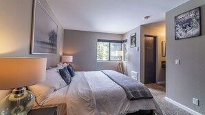 Un dormitorio con una cama grande, lámparas de noche, una ventana y obras de arte en las paredes.