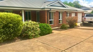 A two-story house with a brick facade, green shutters, and a covered front porch. - Spacious townhouse located in the CBD! (East Wagga Wagga)