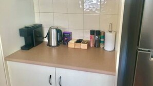 A kitchen with a kettle, a coffee maker, a box of tea, and a roll of paper towels. - Spacious townhouse located in the CBD! (East Wagga Wagga)