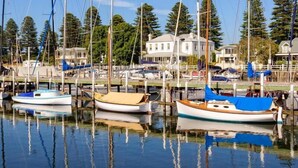 Un port de plaisance où sont amarrés plusieurs bateaux, entouré de maisons et de grands arbres.