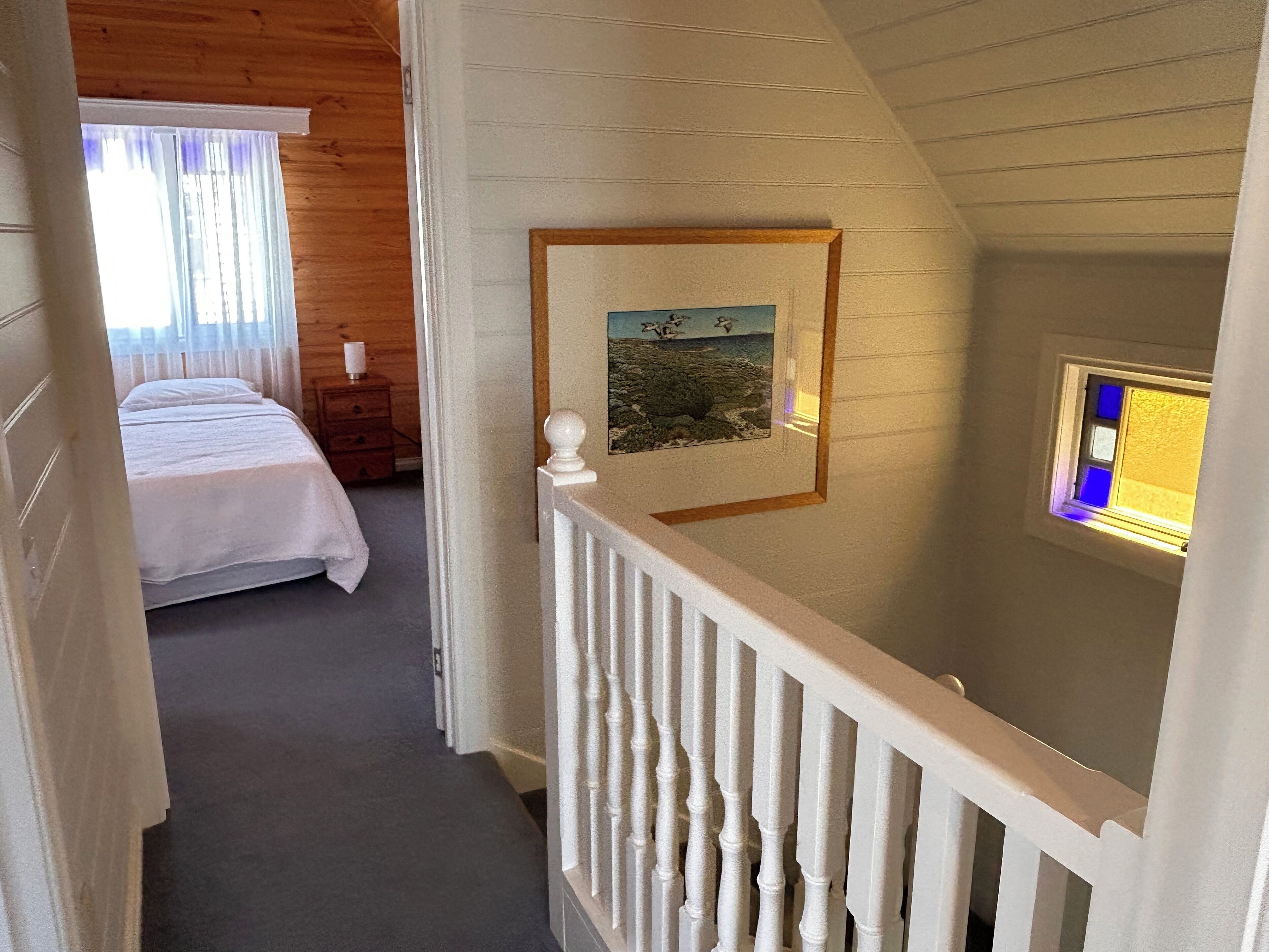 A bedroom with a bed, a nightstand, and a window with curtains.
