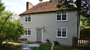 A white two-story house with a tiled roof, a front door, and a small garden with a table and chairs. - Oast Barn Cottage by Bloom Stays -  2 guests  in 1 bedroom (Faversham)