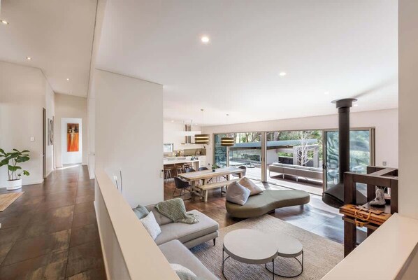 A modern living room with a sofa, a dining area, and a large window.