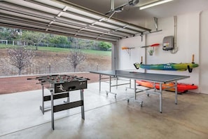An indoor recreational area with a foosball table, ping pong table, and kayaks.