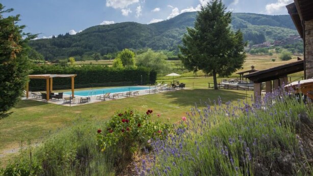 A pool area with a pergola, outdoor seating, and a view of mountains.